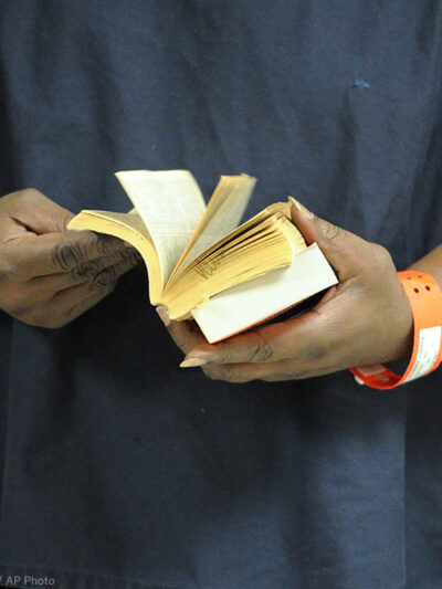 An incarcerated person thumbs through a book