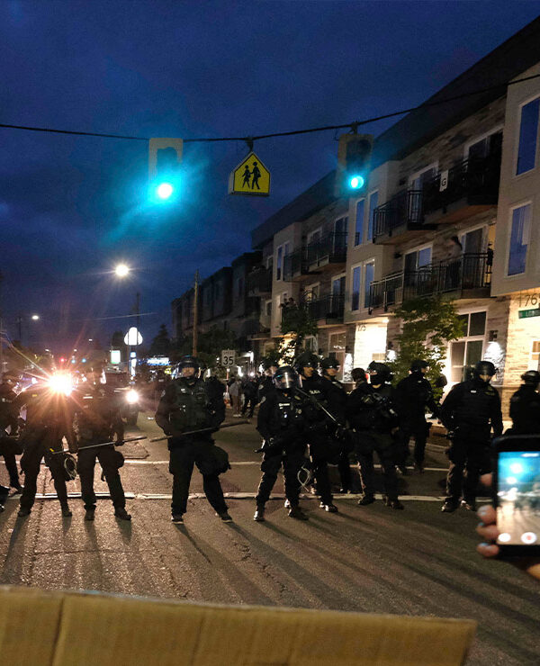 A protester records police in riot gear as they form a wall to push crowds of demonstrators in Portland, Ore., on June 30, 2020, in the wake the murder of George Floyd.