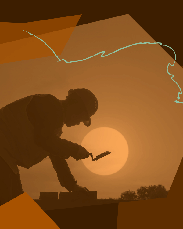 A silhouette of a worker laying bricks in the sun.