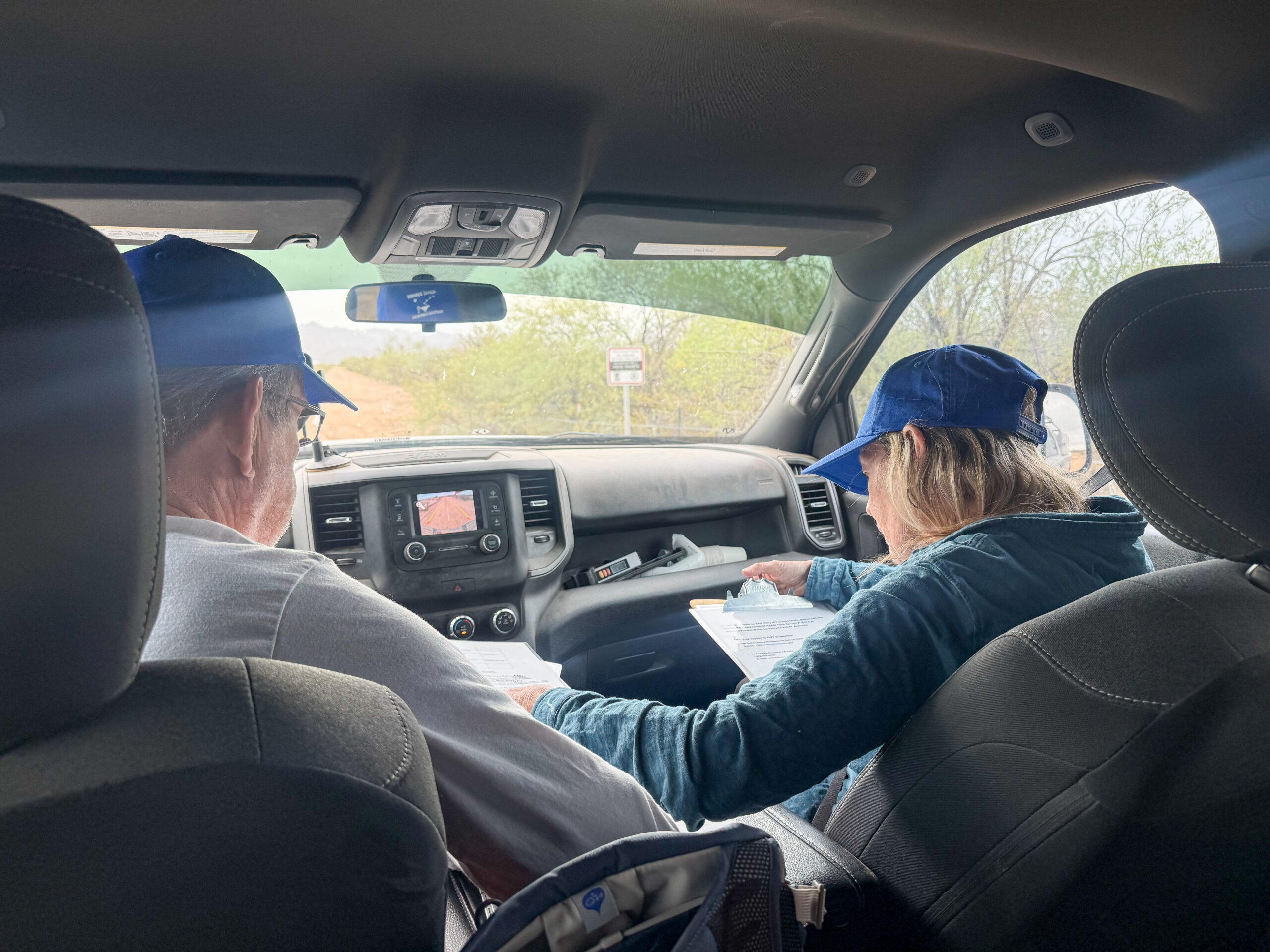 Two people in a car looking at maps and instructions.