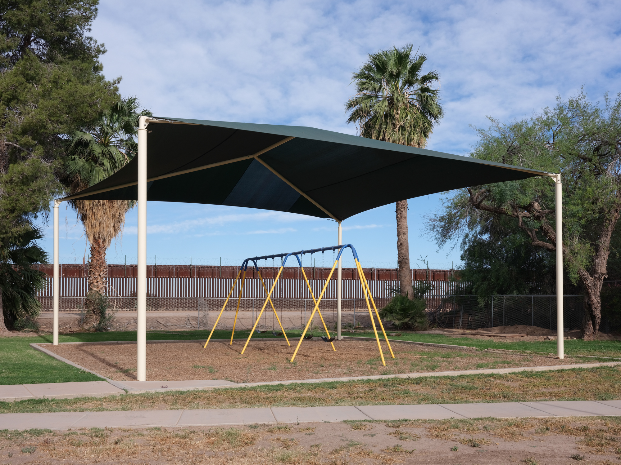 The U.S.-Mexico border wall is seen behind a swing set at Gadsden Park.