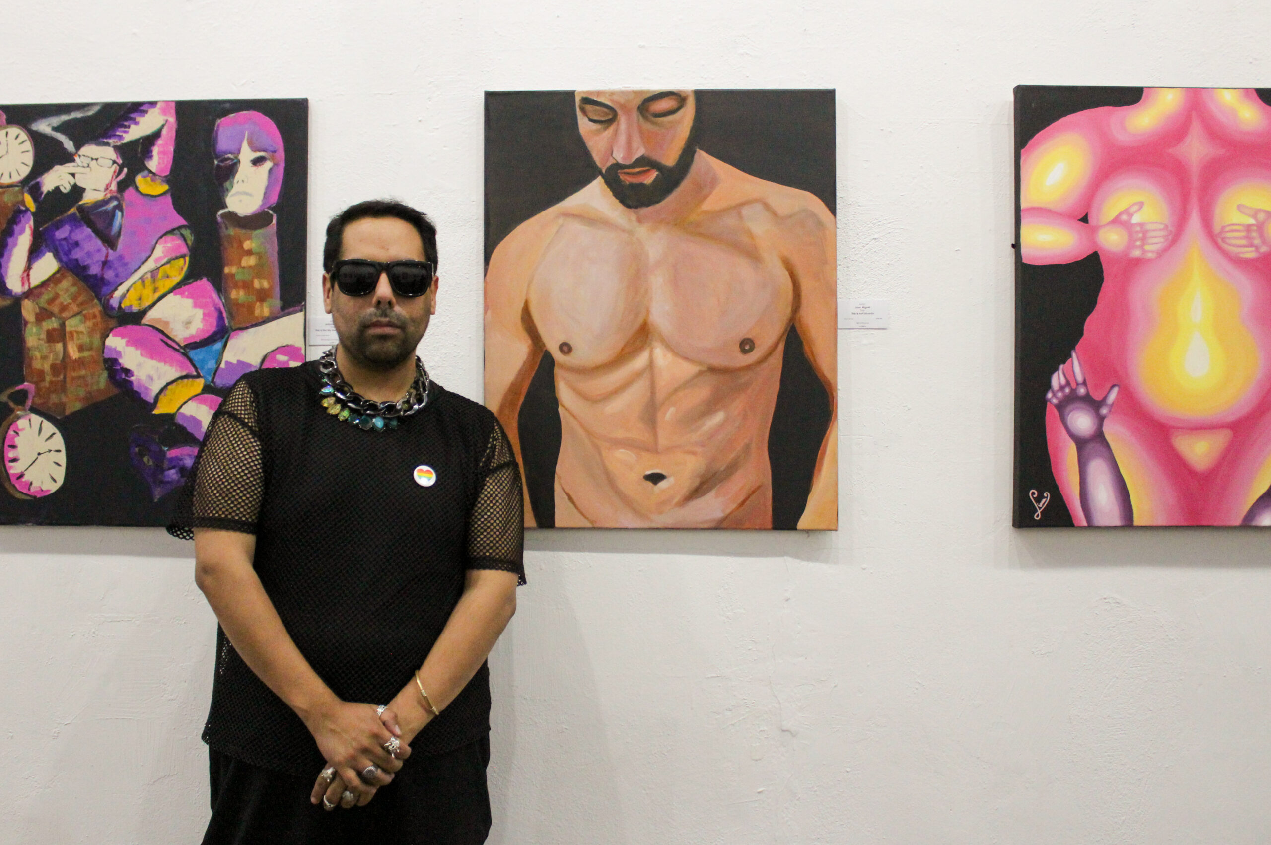 Man standing in front of paintings in a gallery.