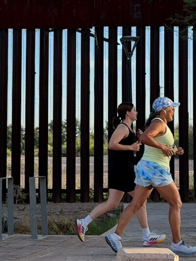 two women running along the U.S.-Mexico border.