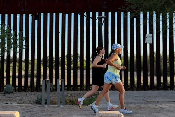 two women running along the U.S.-Mexico border.
