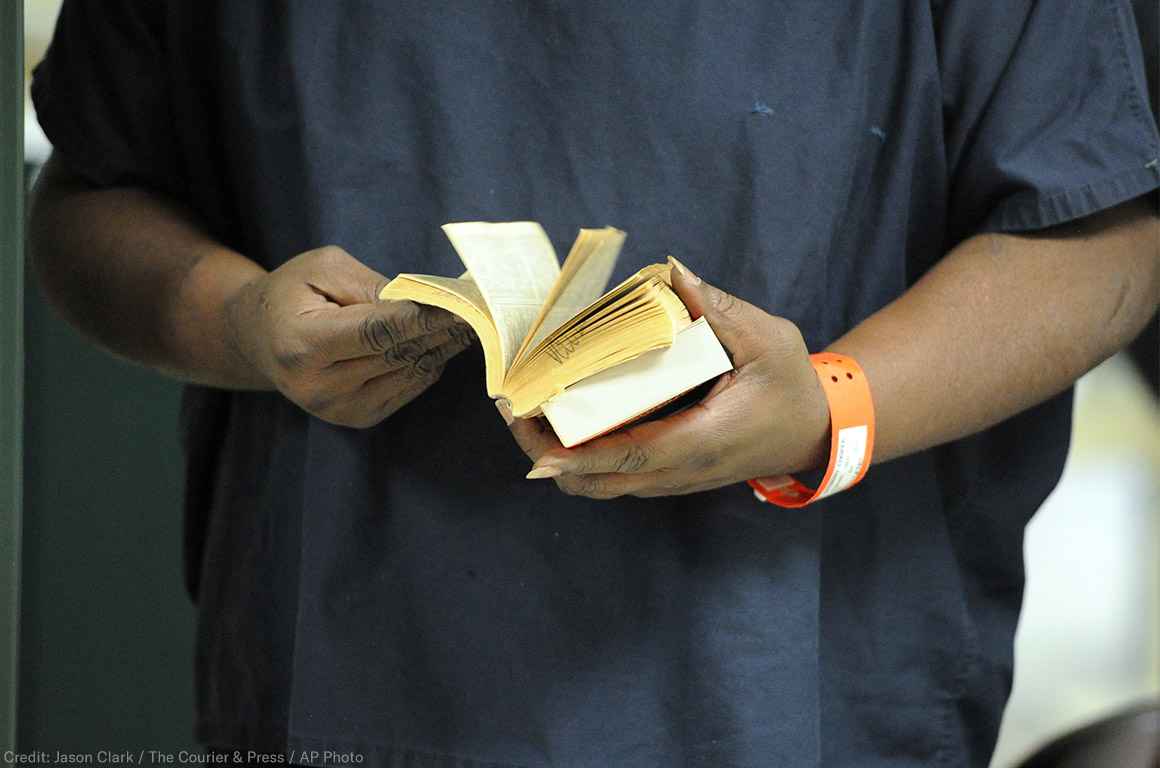 An incarcerated person thumbs through a book