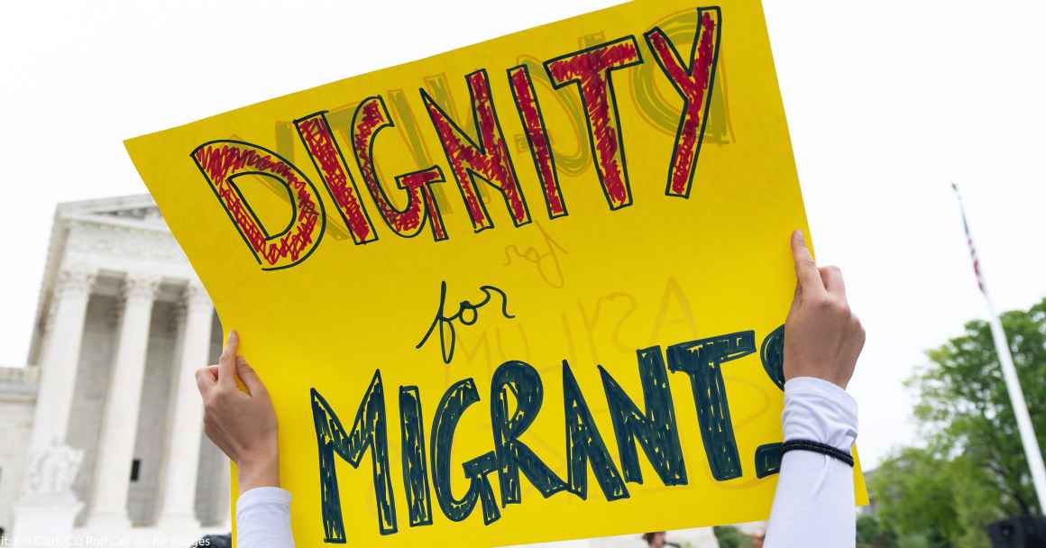 A sign reading "Dignity for Migrants."