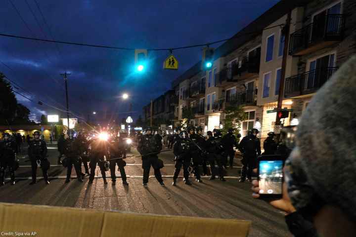 A protester records police in riot gear as they form a wall to push crowds of demonstrators in Portland, Ore., on June 30, 2020, in the wake the murder of George Floyd.