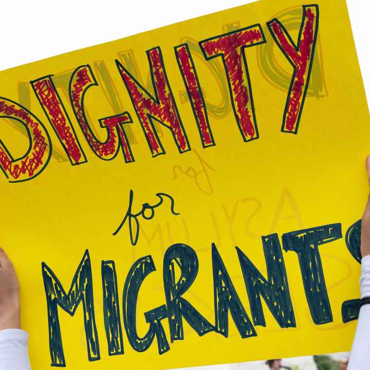 A sign reading "Dignity for Migrants."